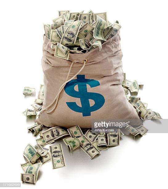 Canvas money bag with dollar symbol is overflowing with dollar bills